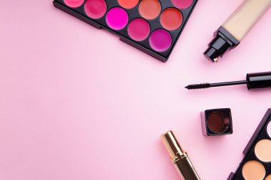 ruj ve kapatıcı paletleri maskara ve temel üzerine pembe bir arka plan ile. Kadınsı aksesuarları kavramı 