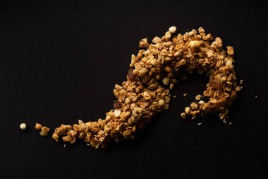 siyah arka plan üzerine eğrisi şeklinde kavrulmuş granola girildi 