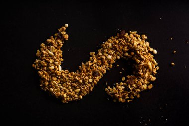 siyah arka plan üzerine eğrisi şeklinde kavrulmuş granola girildi 