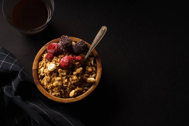Granola ahududu ve böğürtlen ahşap kase ile. Üstten görünüm,