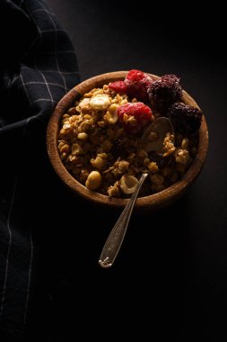 Granola ahududu ve böğürtlen ahşap kase ile. Üstten görünüm,