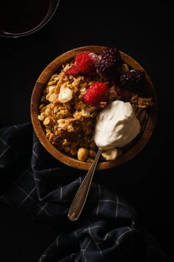Granola ahududu ve böğürtlen ahşap kase dondurma kaşığı ile. Üstten görünüm