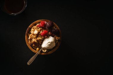 Granola ahududu ve böğürtlen ahşap kase dondurma kaşığı ile. Üstten görünüm,
