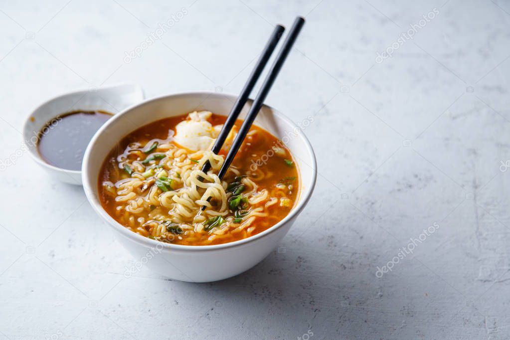 Easy japanese ramen with noodles and pork broth with egg and leek in white bowl on concrete background 