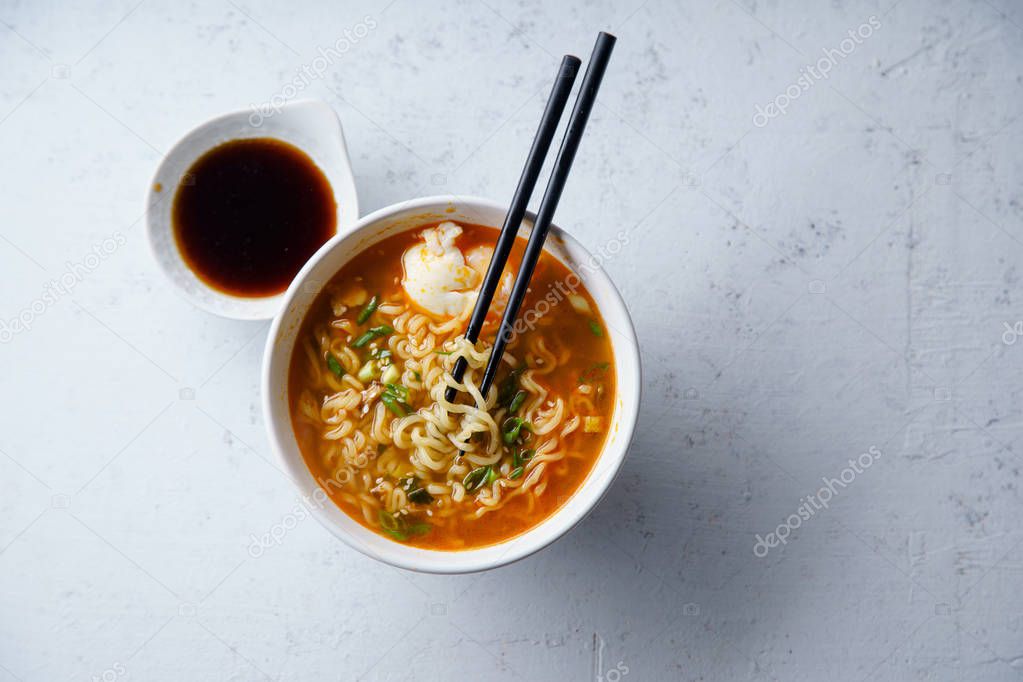 Easy japanese ramen with noodles and pork broth with egg and leek in white bowl on concrete background 