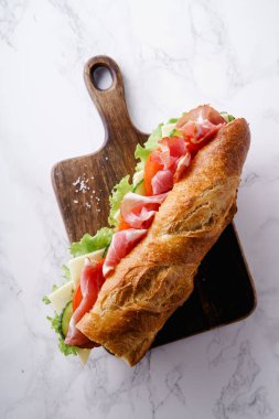 Jambon ve ahşap kesme tahtası üzerinde taze marul ile domates taze baget sandviç Banh'da-mi tarz 