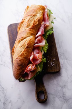 Jambon ve ahşap kesme tahtası üzerinde taze marul ile domates taze baget sandviç Banh'da-mi tarz 