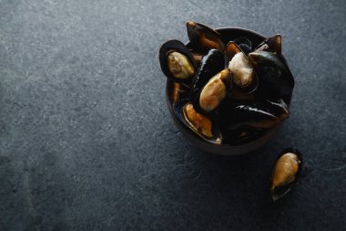 Siyah seramik kasede koyu beton arka planda taze midyeler. 