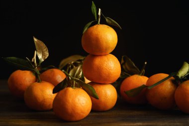 Koyu arka plan üzerinde yeşil yaprakları ile mandalina piramit