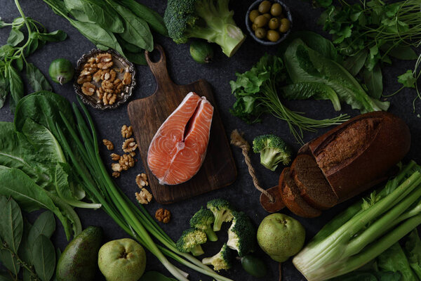 Fresh healthy food composition of vegetables with greens and fruits with raw salmon steak and walnuts with bread 