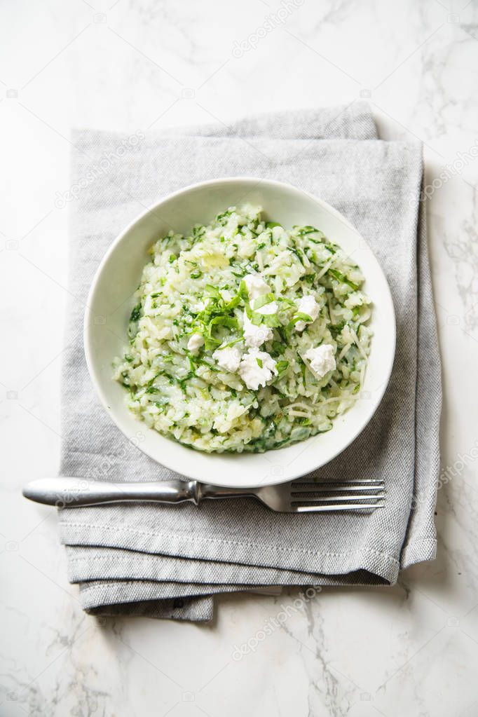 Spinach risotto with fork and napkin on marble background