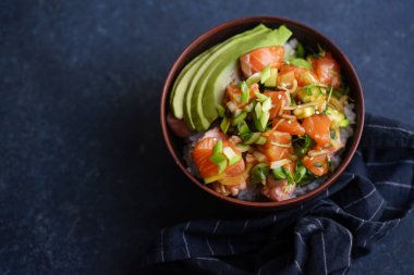 Kase çiğ Marine edilmiş somon ve koyu mavi beton zemin üzerine avokado ile salatalık ile poke