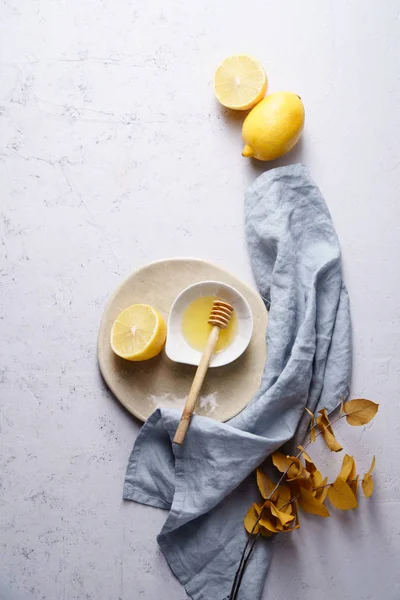 Top view of lemons and honey in bowl on wooden cutting boars with textile, homemade cosmetics concept