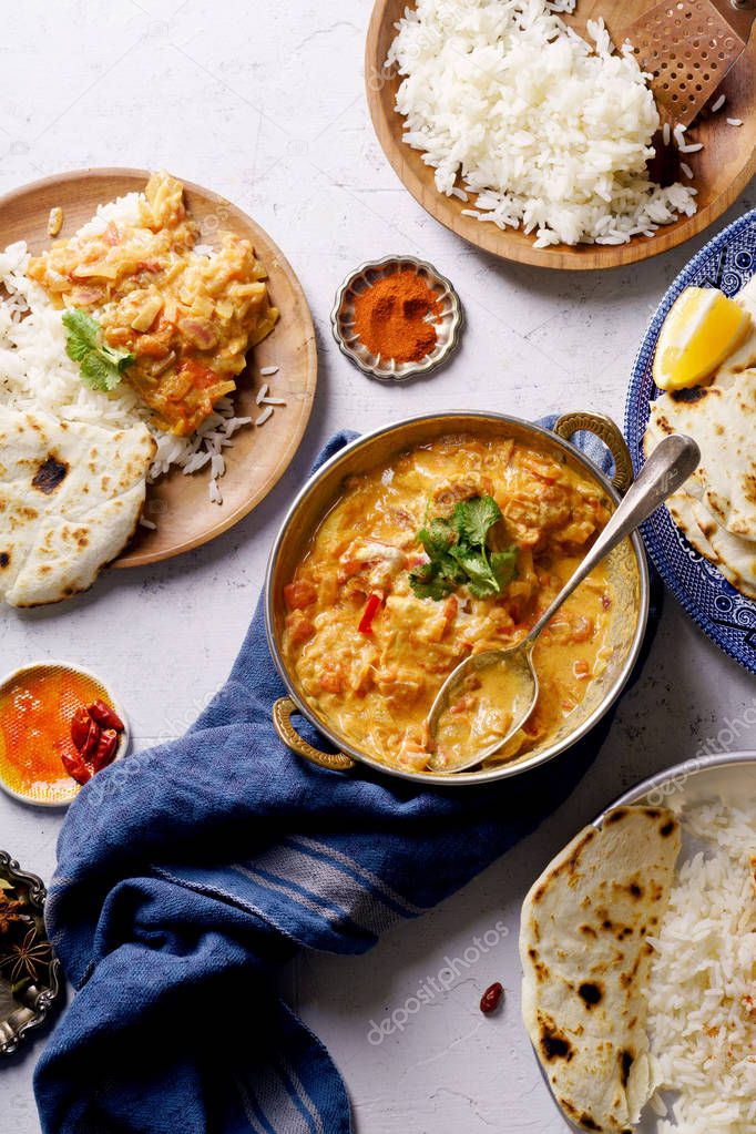 Indian dishes of chicken tikka masala and rice with naan bread and spices 