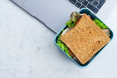 Laptop plastik kap içinde Yeşiller ve jambon ile sağlıklı sandviç Paketli. İş yerinde öğle yemeği için paket servisi olan restoran gıda 