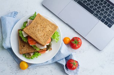 yeşillikleri ile sağlıklı sandviç ve domates ve peynirle dizüstü yakınındaki plaka üzerinde jambon, yemek fikirler için çalışmak