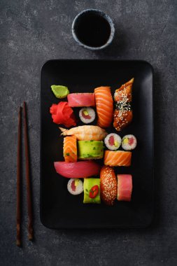 ahşap çubuklar ve kase soya sosu ile tabakta suşi ve rulo