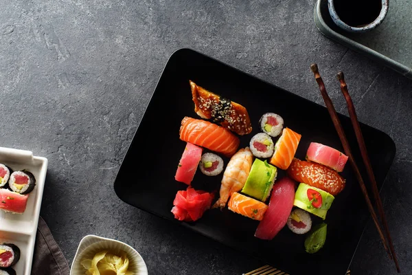 set of sushi and rolls served on plates with wooden chopsticks