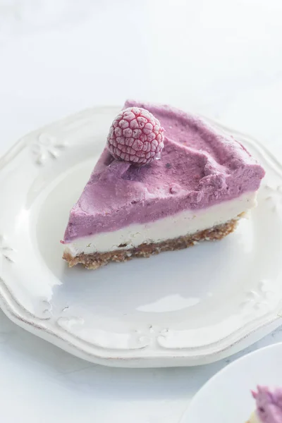 Raw cashew cake with raspberries on plate, concept of gluten-free dessert