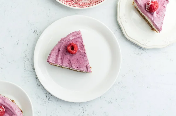 slices of raw cashew cake with raspberries on plates, concept of gluten-free dessert