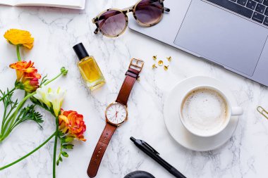 dizüstü bilgisayar ve mermer arka plan üzerinde kol saati ve freesia çiçek ile kapuçino fincan