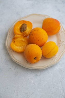 plate with fresh apricots on concrete background  clipart