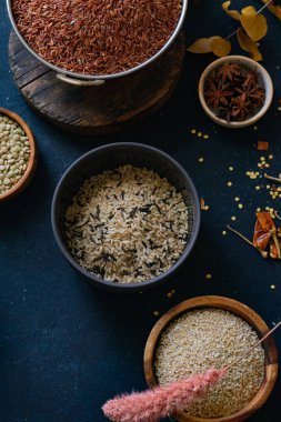 Mavi arka plan üzerinde kaselerde baharat ile pirinç ve tahıl çeşitleri 