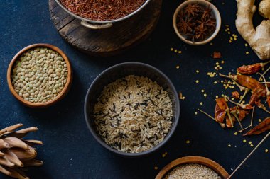 Mavi arka plan üzerinde kaselerde baharat ile pirinç ve tahıl çeşitleri 