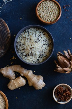 Mavi arka plan üzerinde kaselerde baharat ile pirinç ve tahıl çeşitleri 