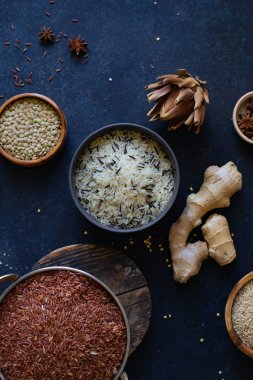 Mavi arka plan üzerinde kaselerde baharat ile pirinç ve tahıl çeşitleri 