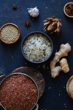 Mavi arka plan üzerinde kaselerde baharat ile pirinç ve tahıl çeşitleri 