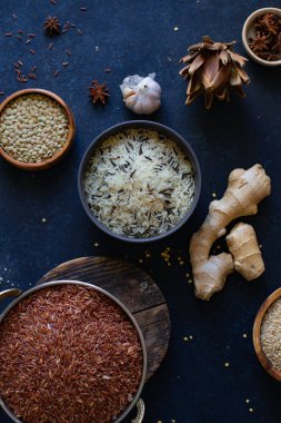 Mavi arka plan üzerinde kaselerde baharat ile pirinç ve tahıl çeşitleri 