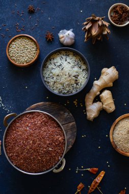 Mavi arka plan üzerinde kaselerde baharat ile pirinç ve tahıl çeşitleri 