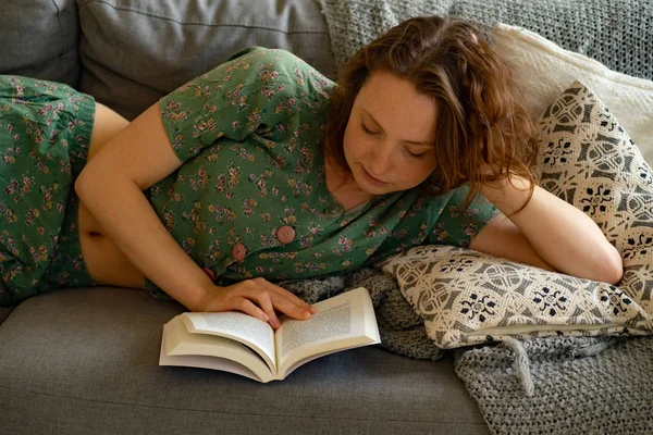 Evdeki Kanepede Uzanmış Kitap Okuyan Genç Bir Kadın — Stok fotoğraf