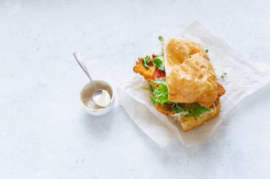 chiabatta sanwich kızarmış tavuk ve salatalık ile domates ve microgreens beyaz kağıt üzerinde, yakın çekim 