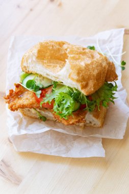 chiabatta sanwich kızarmış tavuk ve salatalık ile domates ve microgreens beyaz kağıt üzerinde, yakın çekim 