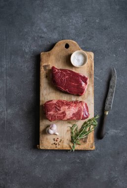 Sarımsak ile biberiye ve deniz tuzu ile vintage kesme tahtası üzerinde Çiğ siyah angus prime sığır biftek 