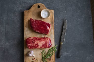 Sarımsak ile biberiye ve deniz tuzu ile vintage kesme tahtası üzerinde Çiğ siyah angus prime sığır biftek 