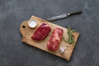 Sarımsak ile biberiye ve deniz tuzu ile vintage kesme tahtası üzerinde Çiğ siyah angus prime sığır biftek 