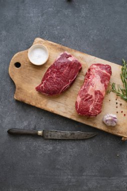 Sarımsak ile biberiye ve deniz tuzu ile vintage kesme tahtası üzerinde Çiğ siyah angus prime sığır biftek 