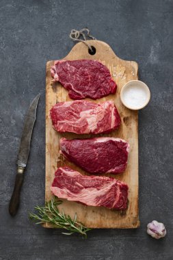 Sarımsak ile biberiye ve deniz tuzu ile vintage kesme tahtası üzerinde Çiğ siyah angus prime sığır biftek 