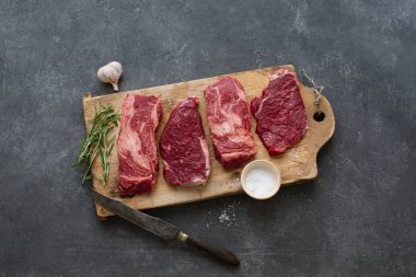 Sarımsak ile biberiye ve deniz tuzu ile vintage kesme tahtası üzerinde Çiğ siyah angus prime sığır biftek 