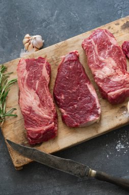 Sarımsak ile biberiye ve deniz tuzu ile vintage kesme tahtası üzerinde Çiğ siyah angus prime sığır biftek 