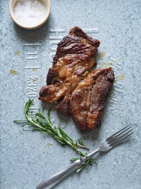 Pişmiş siyah angus prime sığır eti biberiye ve metalik tepsiüzerinde deniz tuzu ile kase ile biftek