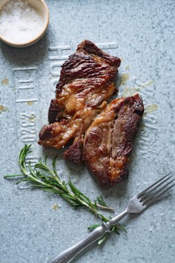 Pişmiş siyah angus prime sığır eti biberiye ve metalik tepsiüzerinde deniz tuzu ile kase ile biftek
