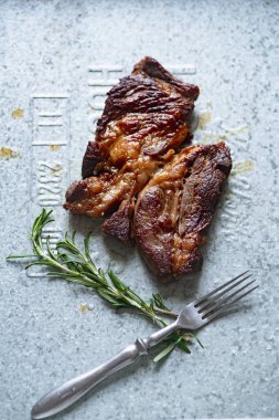 Metalik tepside biberiye ile pişmiş siyah angus prime sığır eti biftek