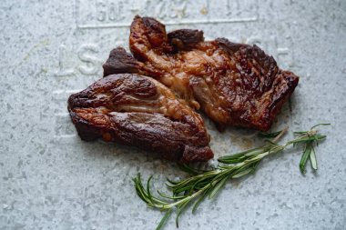 Metalik tepside biberiye ile pişmiş siyah angus prime sığır eti biftek