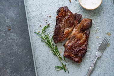 Pişmiş siyah angus prime sığır eti biberiye ve metalik tepsiüzerinde deniz tuzu ile kase ile biftek