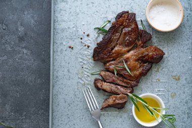 Pişmiş siyah angus prime sığır eti biberiye ve metalik tepsiüzerinde zeytinyağı ile kase ile