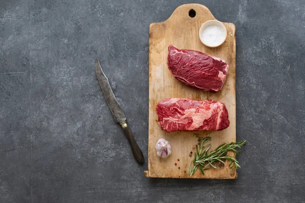 Sarımsak ile biberiye ve deniz tuzu ile vintage kesme tahtası üzerinde Çiğ siyah angus prime sığır biftek 